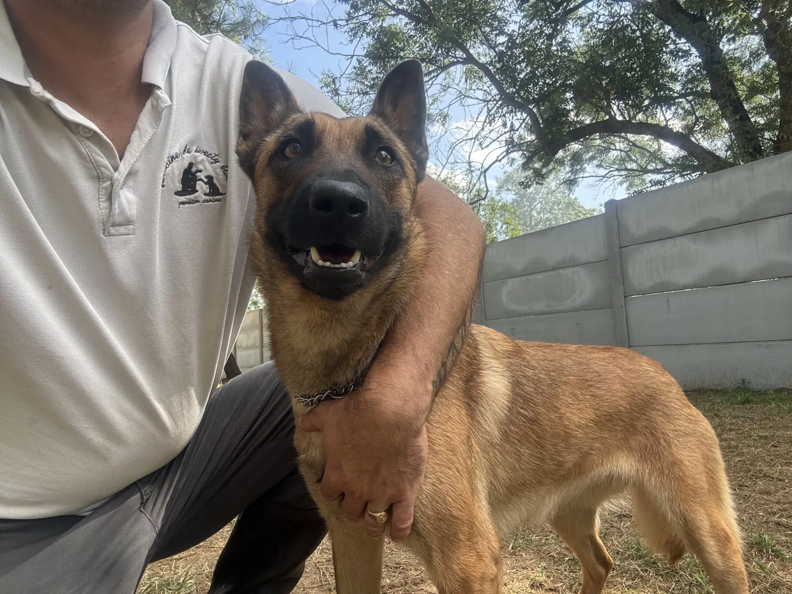 Aurélien accroupi avec un berger malinois dans le parc
